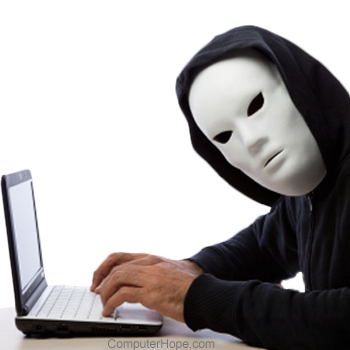 Person wearing a white mask and black hooded jacket using a laptop.